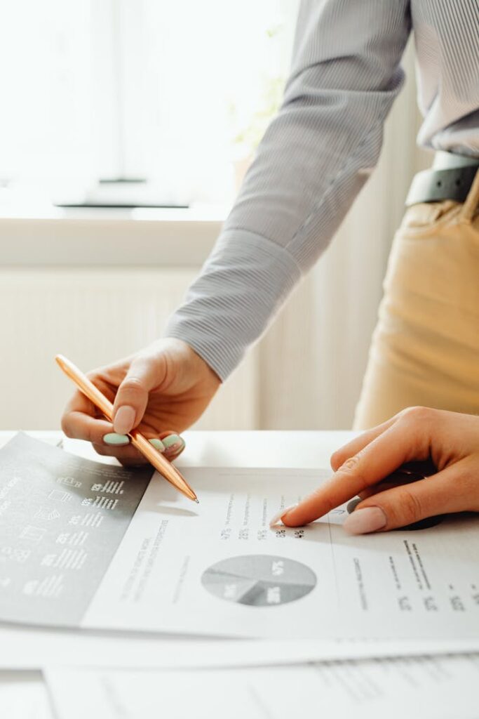 pexels-photo-7681094 Close-up of hands reviewing financial documents and graphs in an office setting.